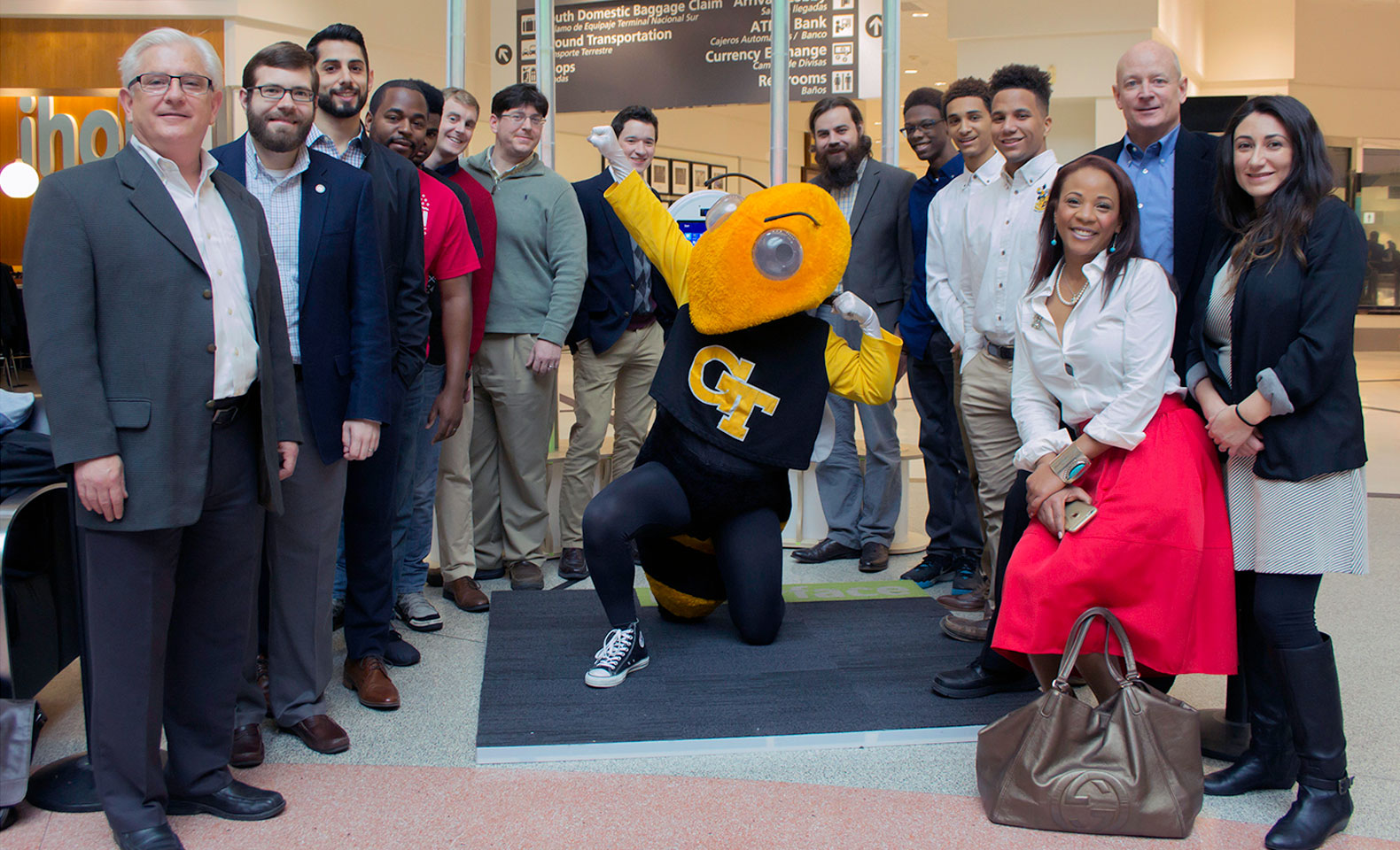 Group photo of project participants with the booth at the airport, with Buzz in the center